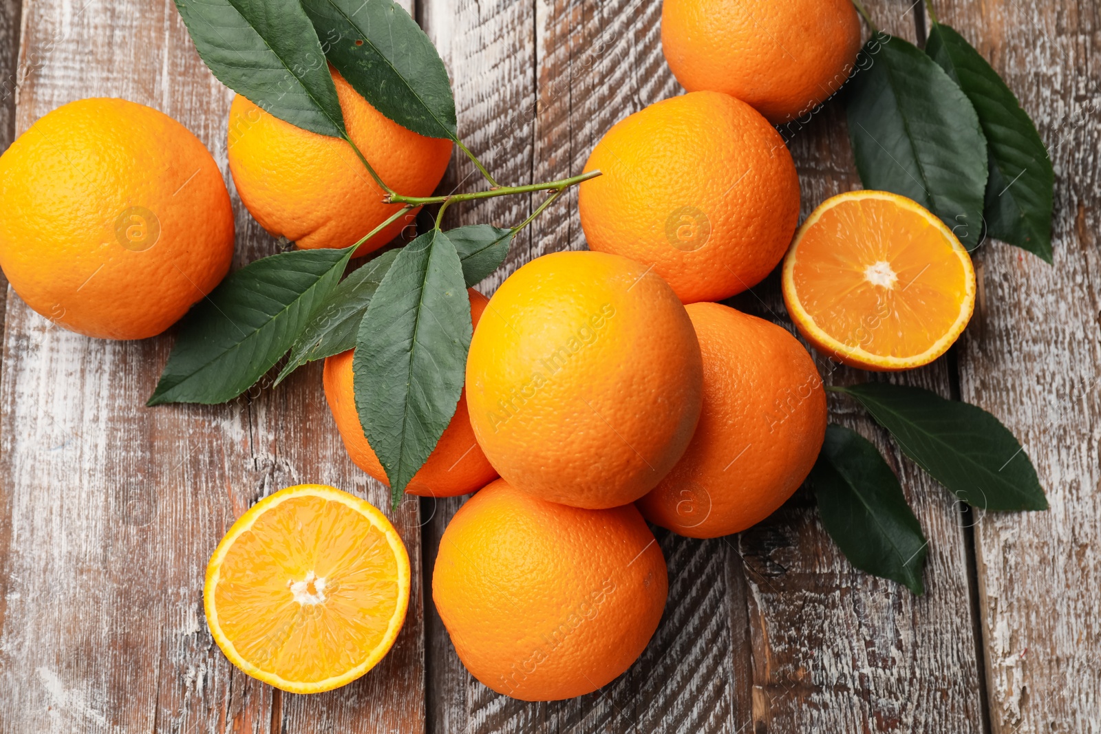 Photo of Fresh oranges and leaves on wooden table, flat lay