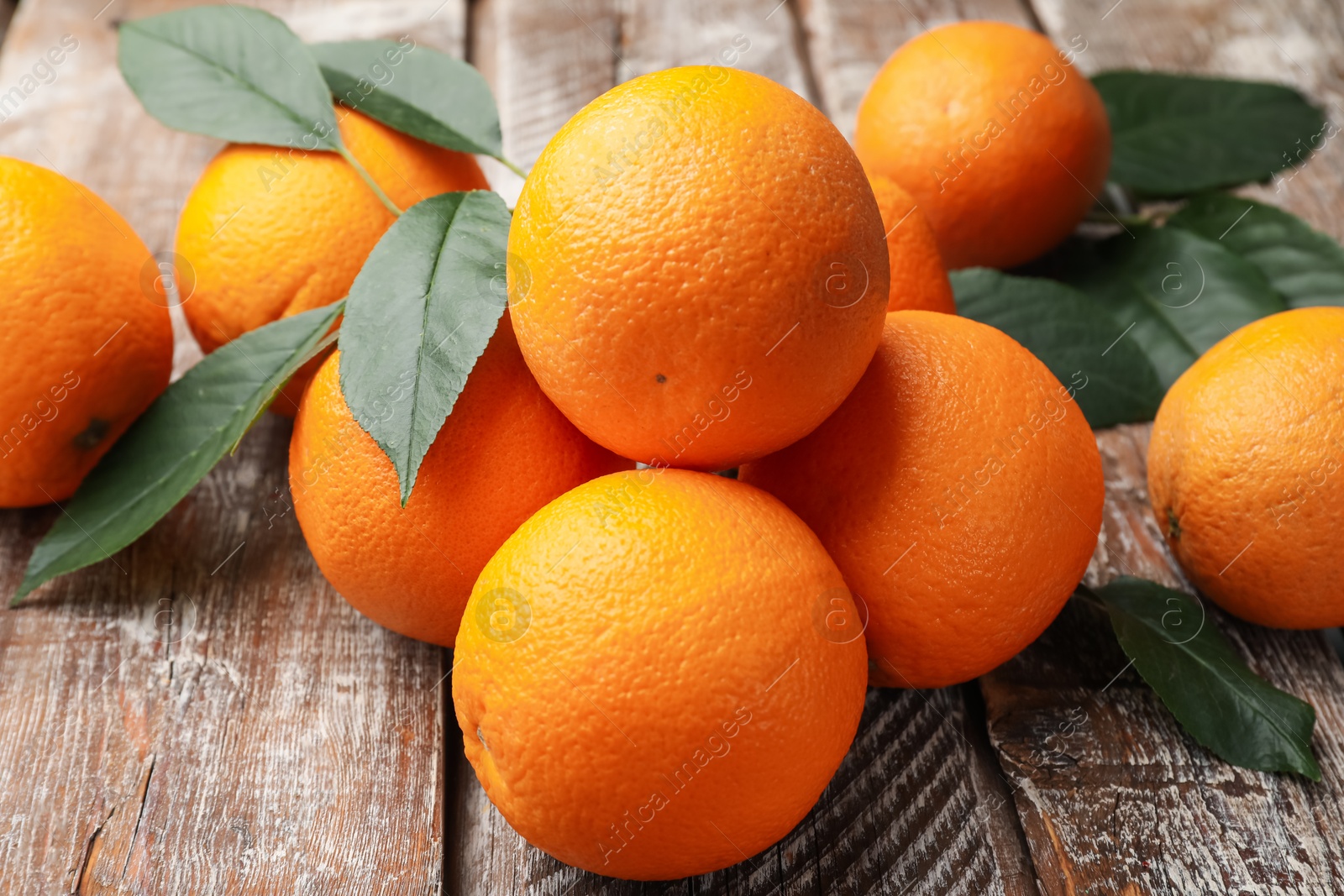 Fresh oranges and leaves on wooden table, closeup Photo of Fresh oranges and leaves on wooden table, closeup