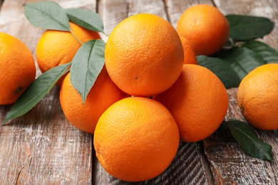Photo of Fresh oranges and leaves on wooden table, closeup