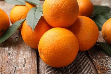 Photo of Fresh oranges and leaves on wooden table, closeup