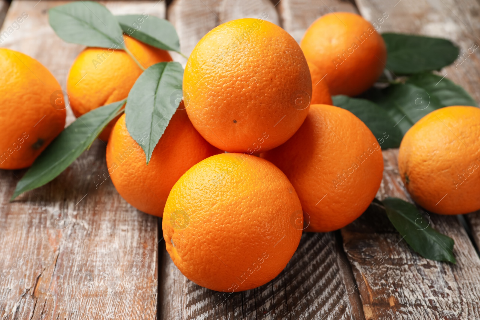 Fresh oranges and leaves on wooden table, closeup Photo of Fresh oranges and leaves on wooden table, closeup