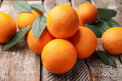 Photo of Fresh oranges and leaves on wooden table, closeup