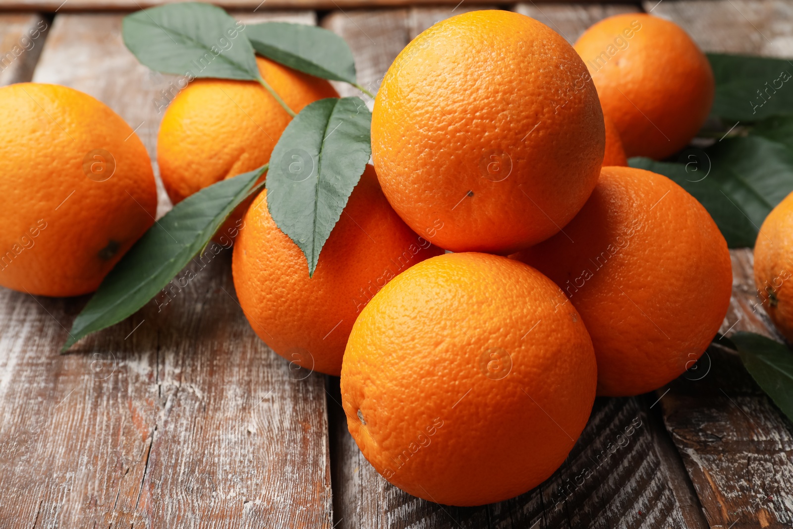 Fresh oranges and leaves on wooden table, closeup Photo of Fresh oranges and leaves on wooden table, closeup