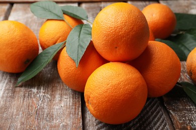 Photo of Fresh oranges and leaves on wooden table, closeup