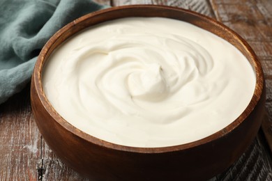Photo of Delicious sour cream in bowl on wooden table, closeup