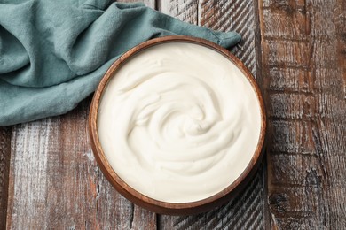 Photo of Delicious sour cream in bowl on wooden table, top view