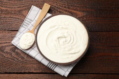 Photo of Delicious sour cream in bowl and spoon on wooden table, top view