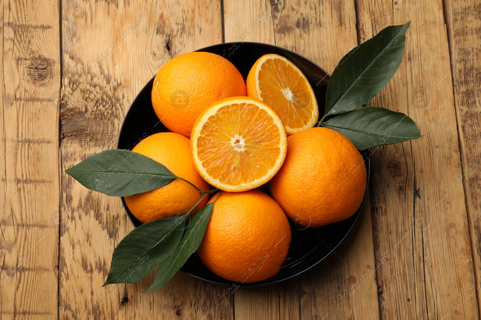 Fresh ripe oranges and leaves on wooden table, top view Photo of Fresh ripe oranges and leaves on wooden table, top view