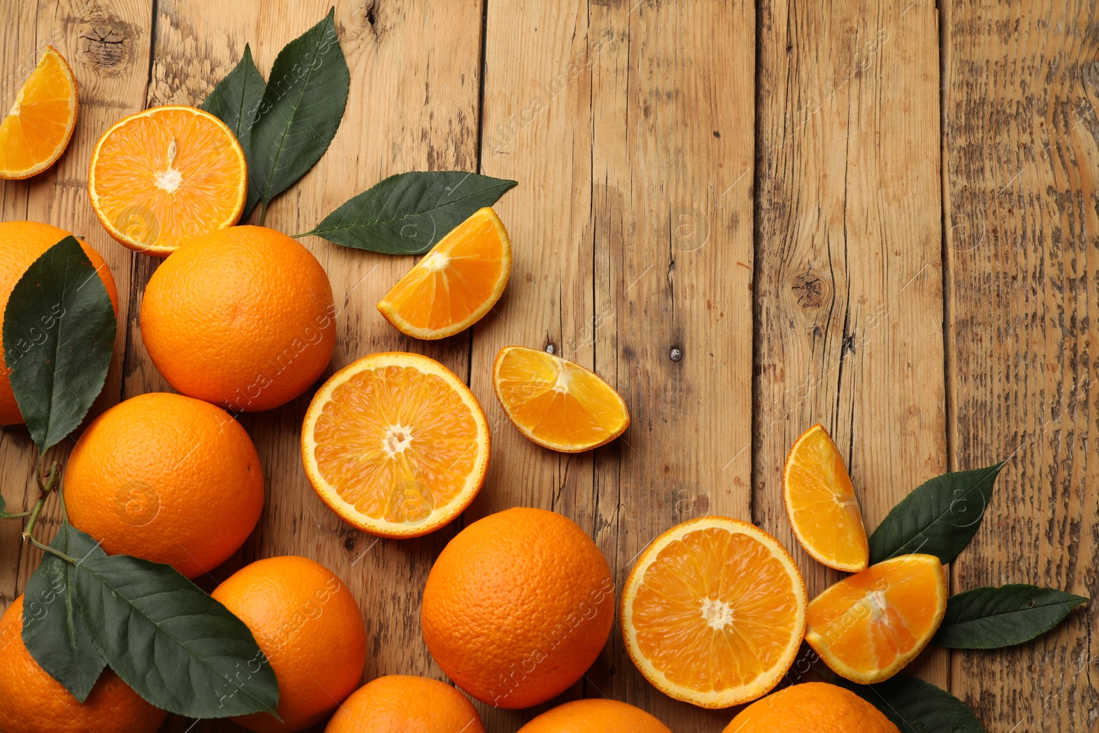 Fresh ripe oranges and leaves on wooden table, flat lay. Space for text Photo of Fresh ripe oranges and leaves on wooden table, flat lay. Space for text