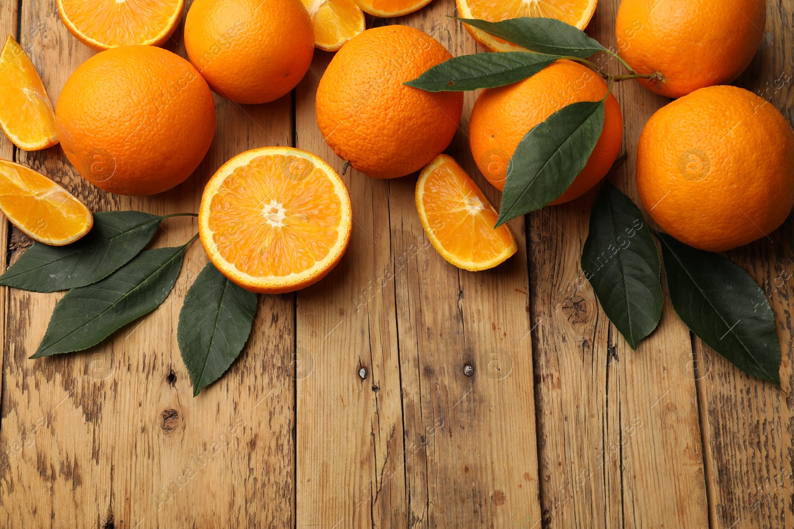 Fresh ripe oranges and leaves on wooden table, flat lay. Space for text Photo of Fresh ripe oranges and leaves on wooden table, flat lay. Space for text