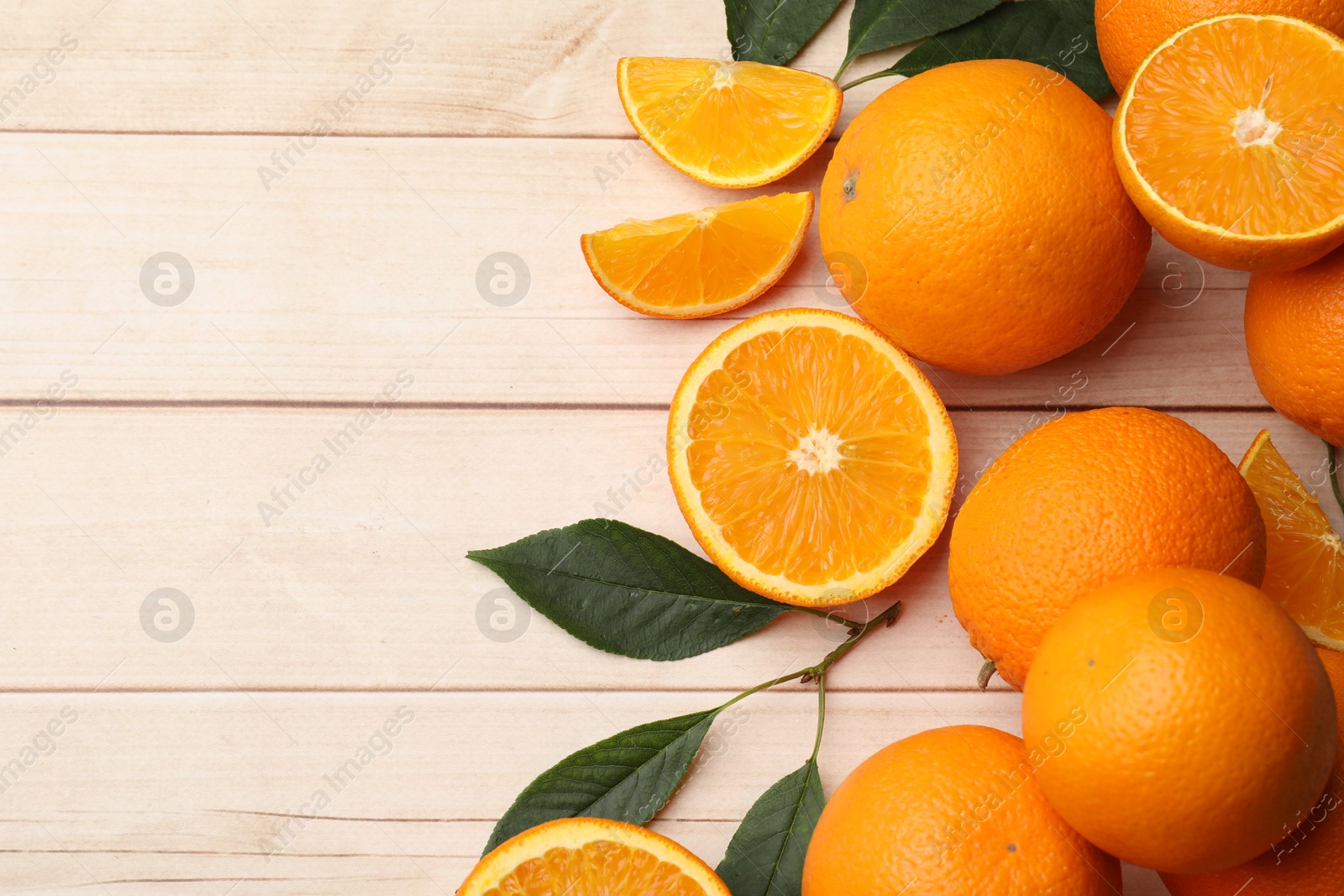 Fresh ripe oranges and leaves on light wooden table, flat lay. Space for text Photo of Fresh ripe oranges and leaves on light wooden table, flat lay. Space for text