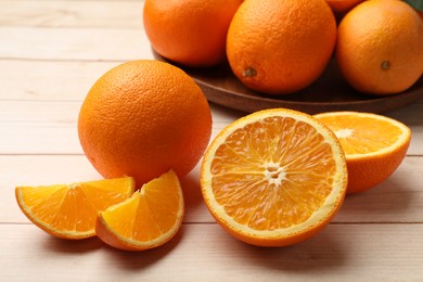 Photo of Fresh ripe oranges on light wooden table, closeup