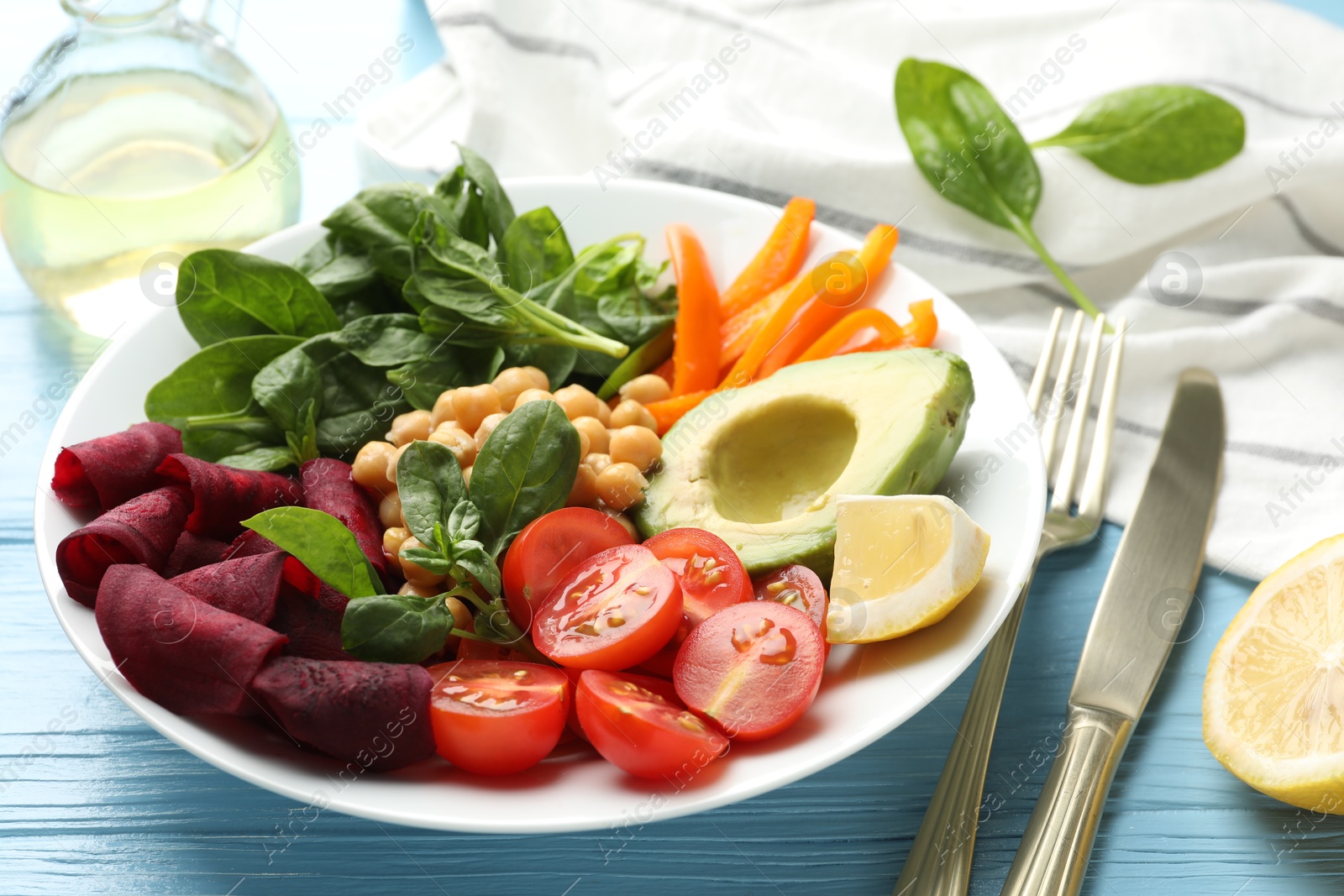 Different healthy vegetarian food and cutlery on light blue wooden table, closeup Photo of Different healthy vegetarian food and cutlery on light blue wooden table, closeup