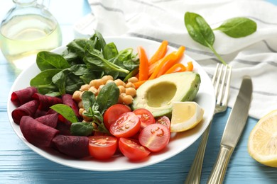 Photo of Different healthy vegetarian food and cutlery on light blue wooden table, closeup