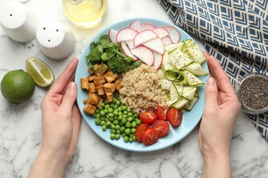 Photo of Woman with different healthy vegetarian food at white marble table, top view