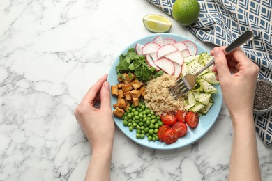 Photo of Woman eating different healthy vegetarian food at white marble table, top view. Space for text