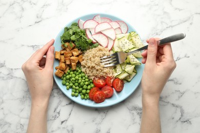 Photo of Woman eating different healthy vegetarian food at white marble table, top view
