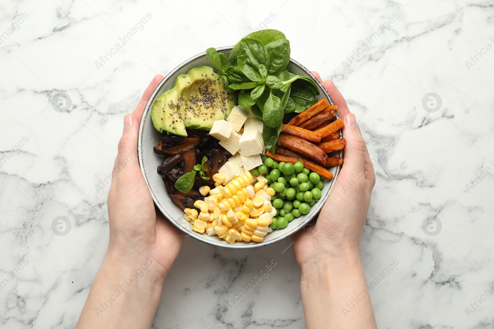 Healthy vegetarian food. Woman with delicious Buddha bowl at white marble table, top view Photo of Healthy vegetarian food. Woman with delicious Buddha bowl at white marble table, top view