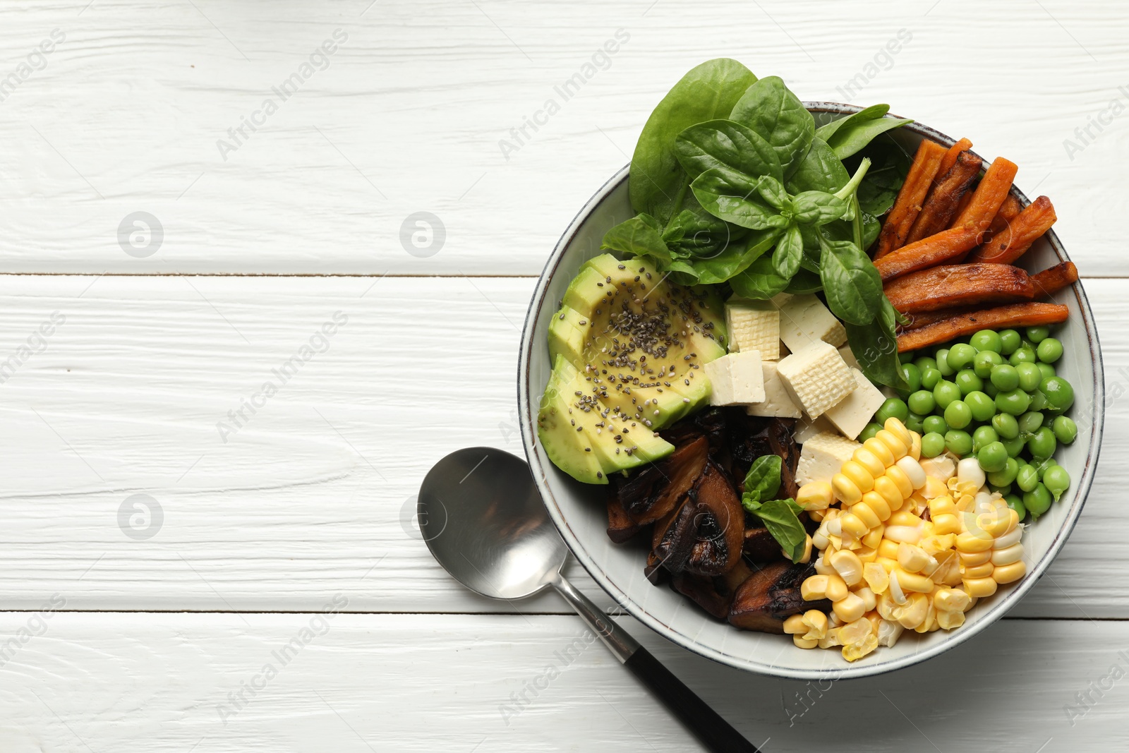 Healthy vegetarian food. Delicious Buddha bowl with tofu, mushrooms, avocado and vegetables on white wooden table, top view. Space for text Photo of Healthy vegetarian food. Delicious Buddha bowl with tofu, mushrooms, avocado and vegetables on white wooden table, top view. Space for text