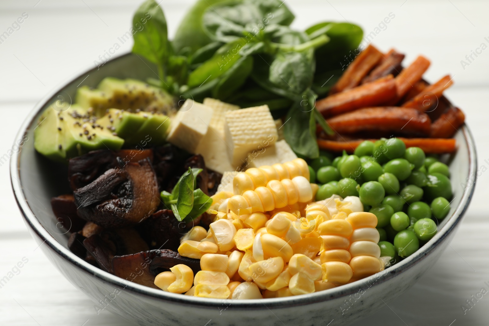 Healthy vegetarian food. Delicious Buddha bowl with tofu, mushrooms, avocado and vegetables on white table, closeup Photo of Healthy vegetarian food. Delicious Buddha bowl with tofu, mushrooms, avocado and vegetables on white table, closeup