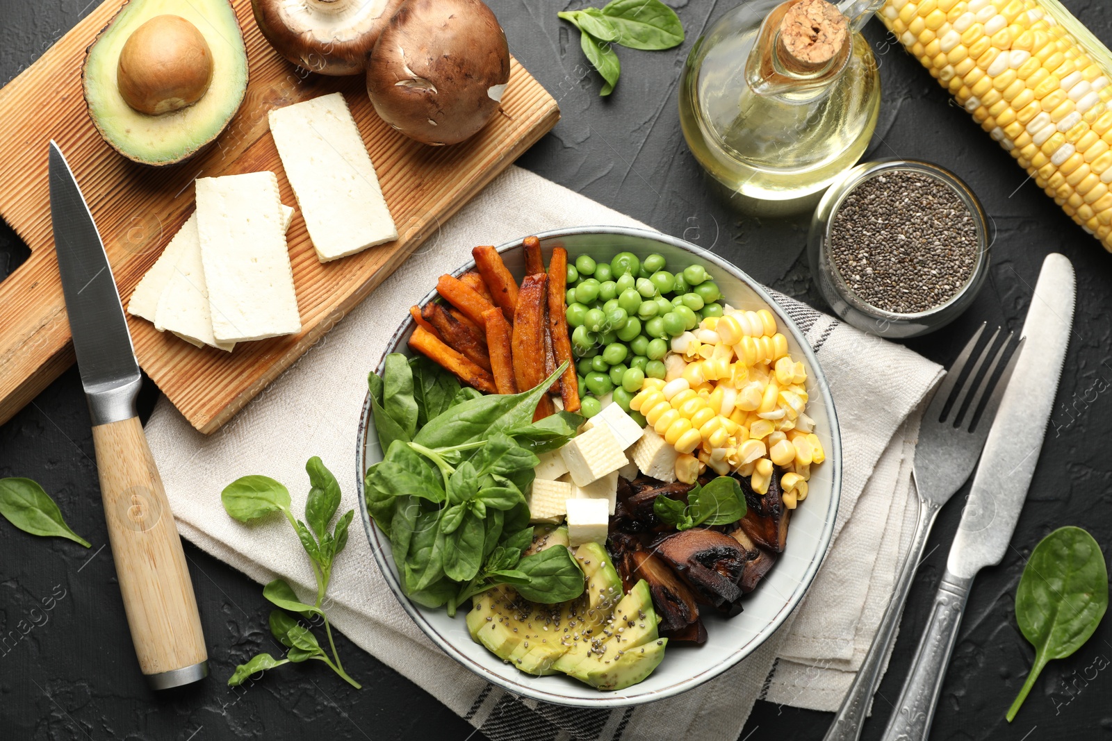 Healthy vegetarian food. Delicious Buddha bowl and ingredients on black table, flat lay Photo of Healthy vegetarian food. Delicious Buddha bowl and ingredients on black table, flat lay