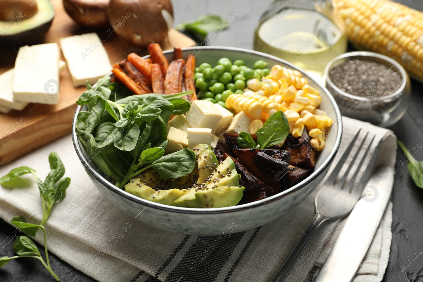 Healthy vegetarian food. Delicious Buddha bowl and ingredients on black table, closeup Photo of Healthy vegetarian food. Delicious Buddha bowl and ingredients on black table, closeup