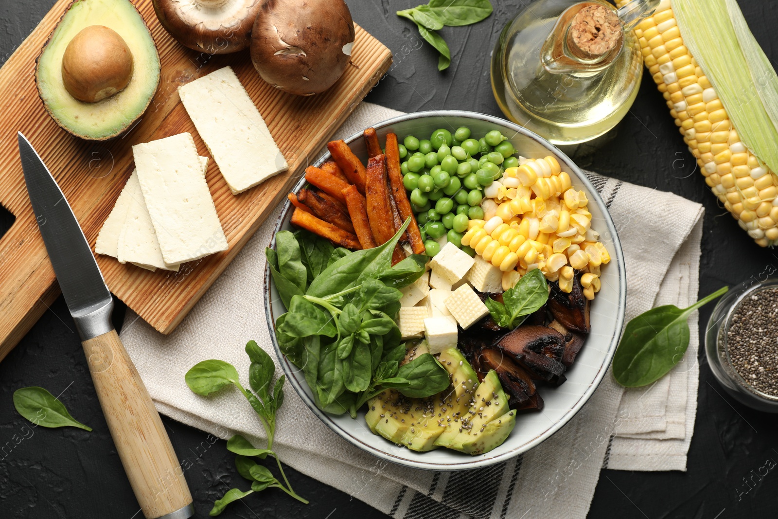 Healthy vegetarian food. Delicious Buddha bowl and ingredients on black table, flat lay Photo of Healthy vegetarian food. Delicious Buddha bowl and ingredients on black table, flat lay