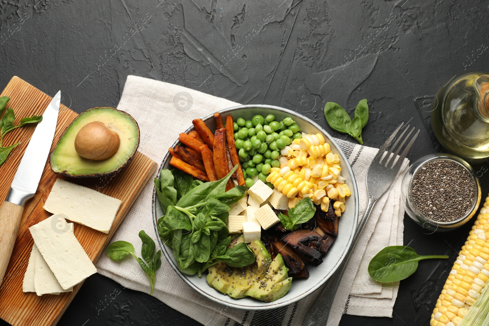 Healthy vegetarian food. Delicious Buddha bowl and ingredients on black table, flat lay Photo of Healthy vegetarian food. Delicious Buddha bowl and ingredients on black table, flat lay