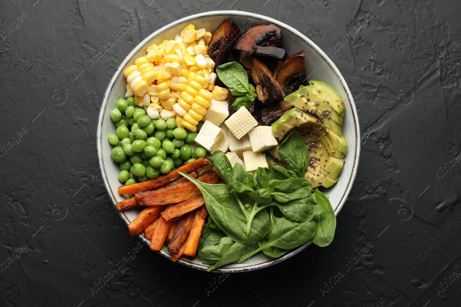 Healthy vegetarian food. Delicious Buddha bowl on black table, top view Photo of Healthy vegetarian food. Delicious Buddha bowl on black table, top view
