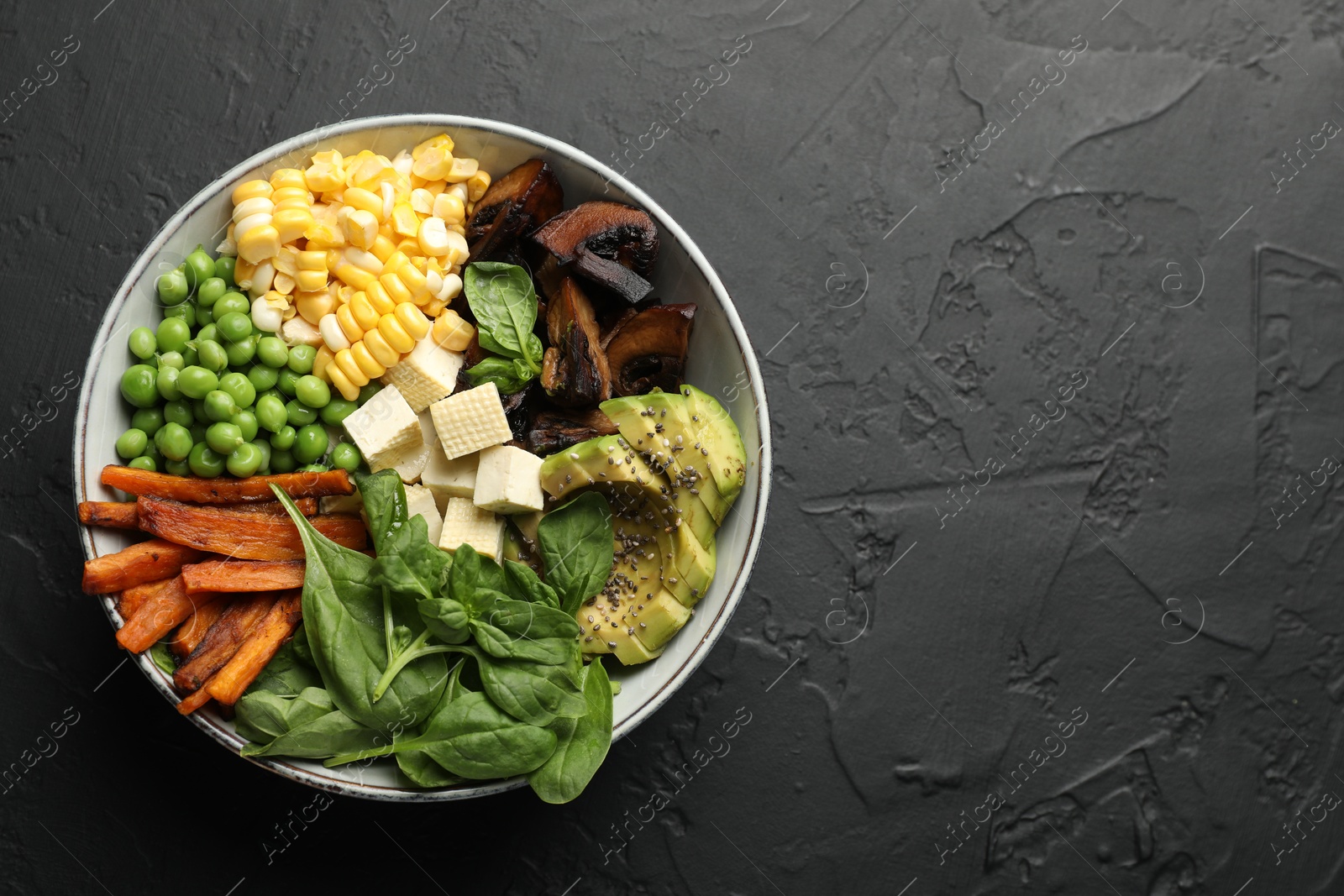Photo of Healthy vegetarian food. Delicious Buddha bowl on black table, top view. Space for text