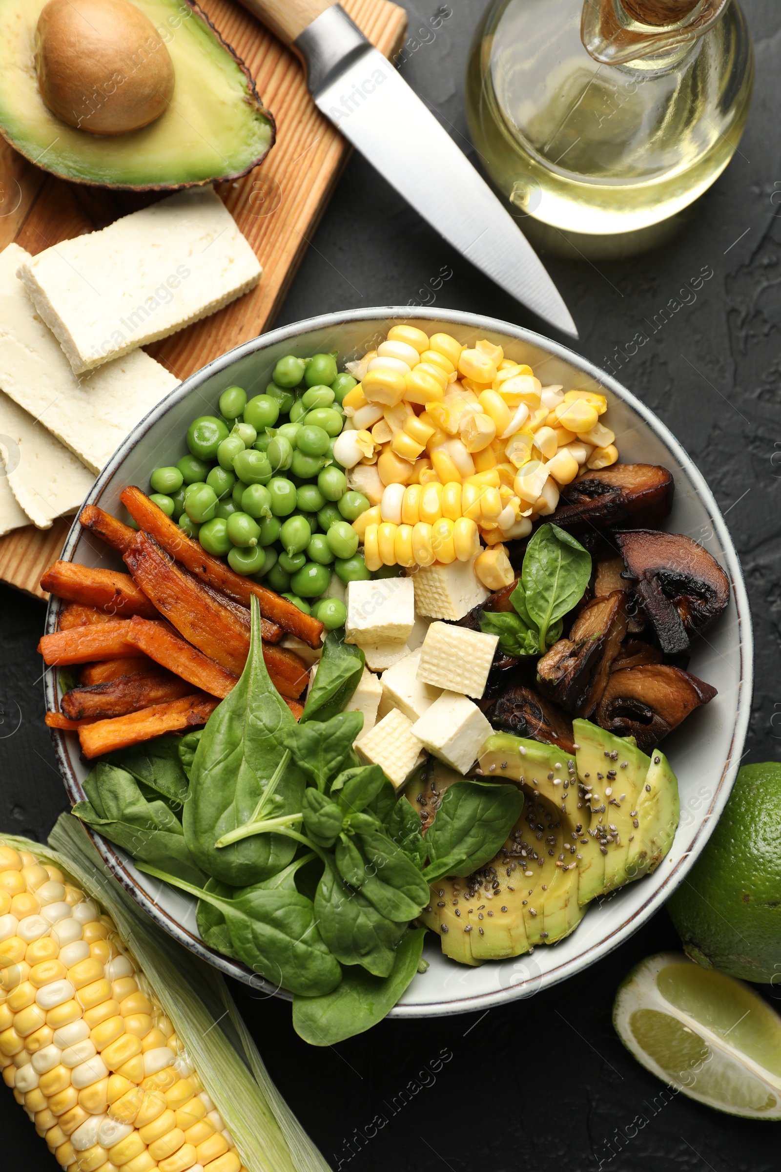 Healthy vegetarian food. Delicious Buddha bowl and ingredients on black table, flat lay Photo of Healthy vegetarian food. Delicious Buddha bowl and ingredients on black table, flat lay
