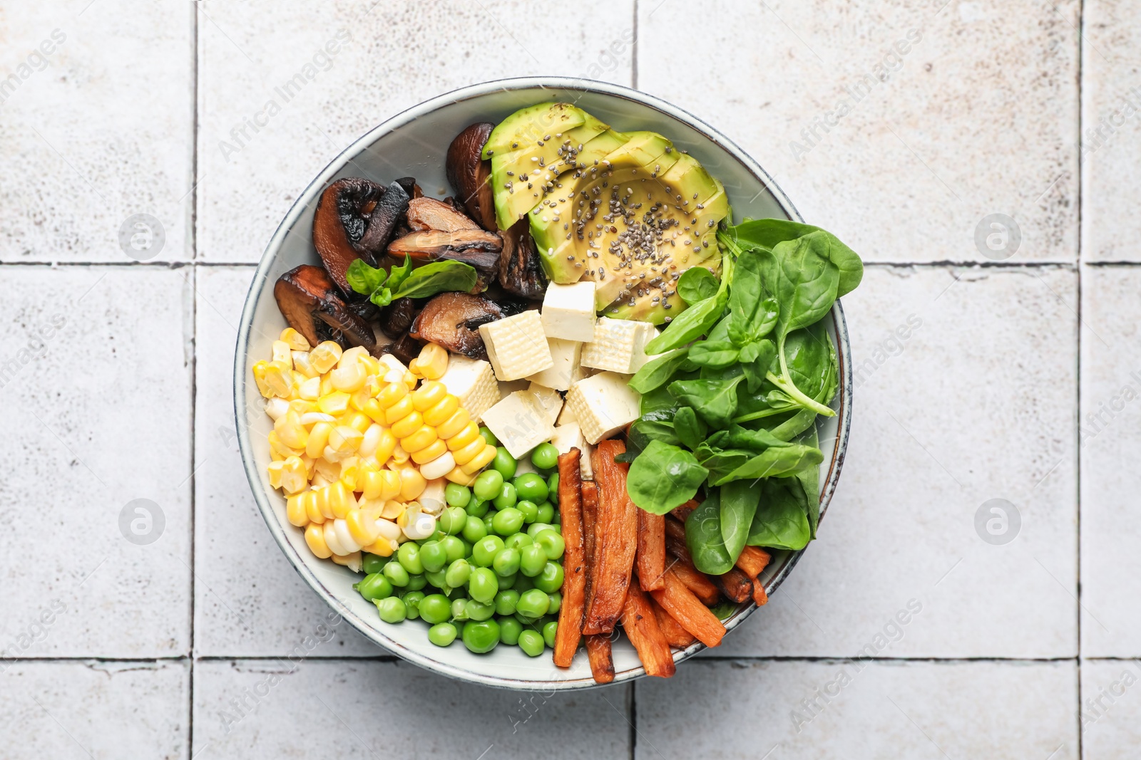 Healthy vegetarian food. Delicious Buddha bowl on light tiled table, top view Photo of Healthy vegetarian food. Delicious Buddha bowl on light tiled table, top view