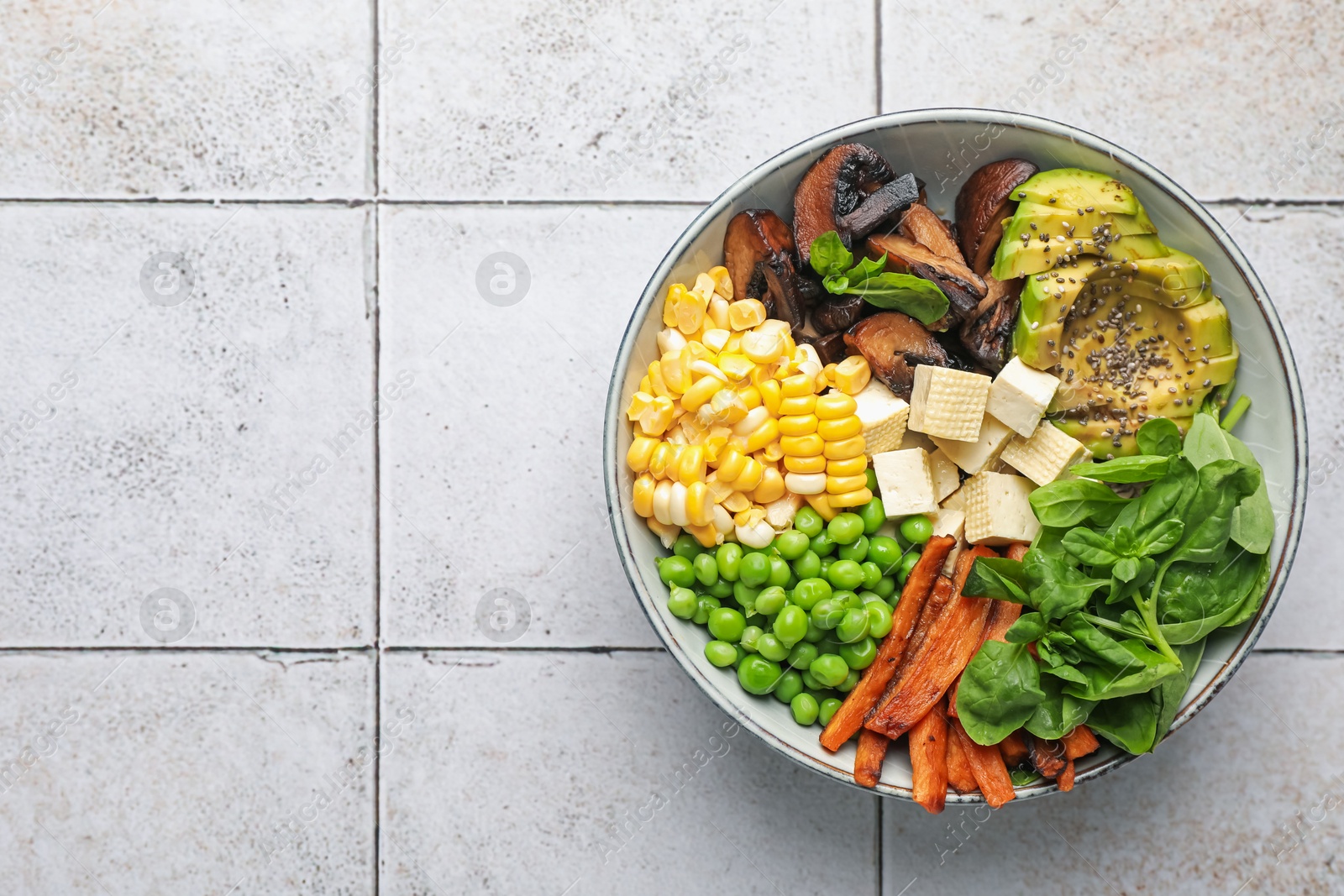 Healthy vegetarian food. Delicious Buddha bowl on light tiled table, top view. Space for text Photo of Healthy vegetarian food. Delicious Buddha bowl on light tiled table, top view. Space for text