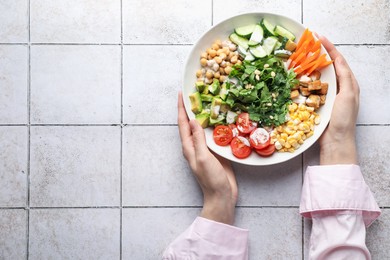 Photo of Woman with different healthy vegetarian food at light tiled table, top view. Space for text