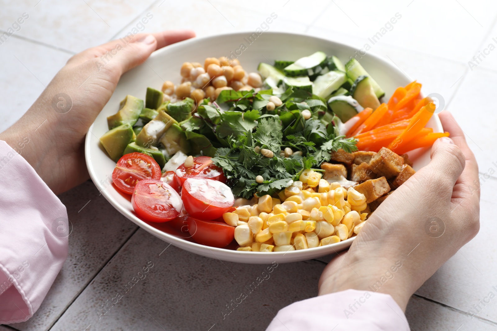 Woman with different healthy vegetarian food at light tiled table, closeup Photo of Woman with different healthy vegetarian food at light tiled table, closeup