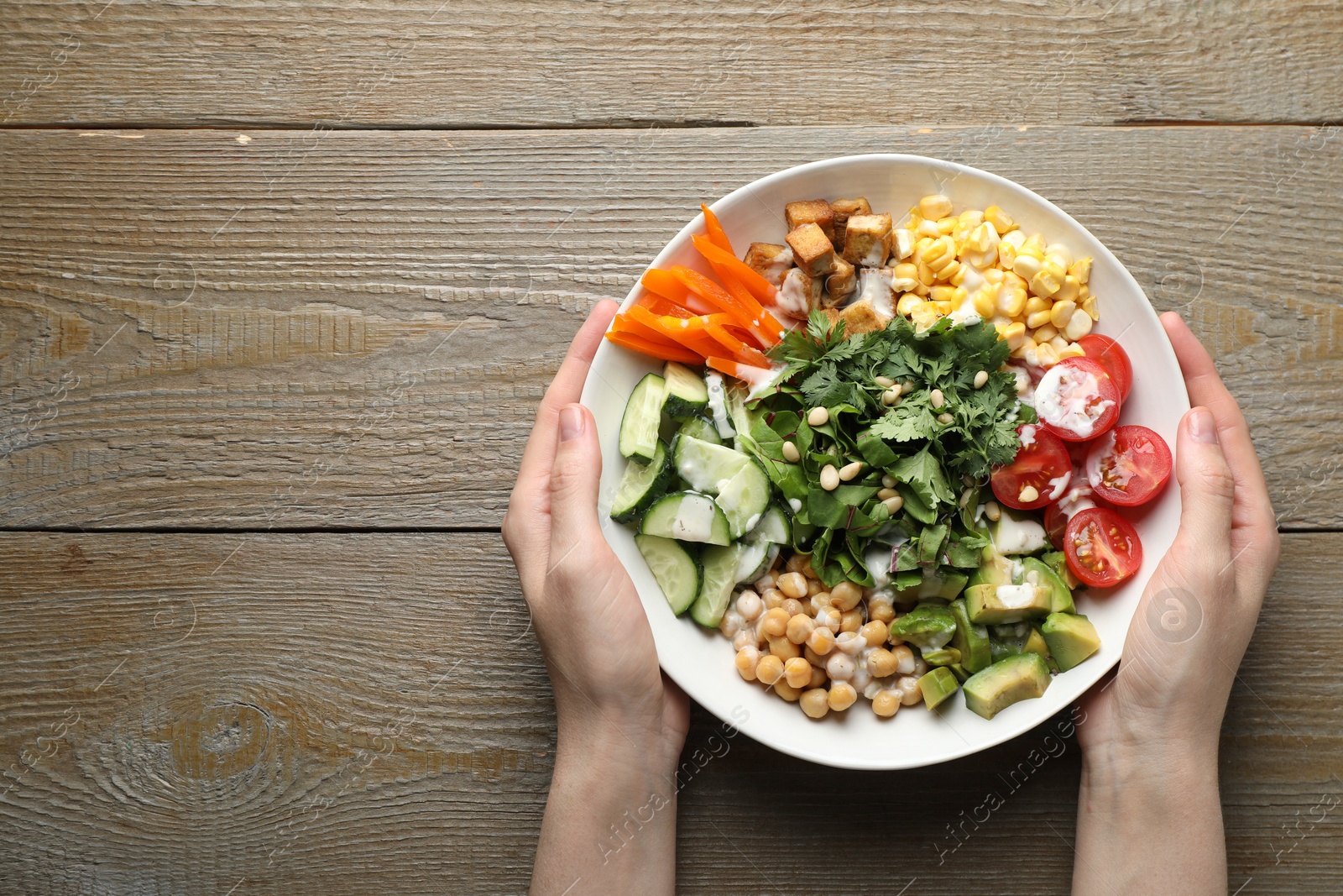 Woman with different healthy vegetarian food at wooden table, top view. Space for text Photo of Woman with different healthy vegetarian food at wooden table, top view. Space for text