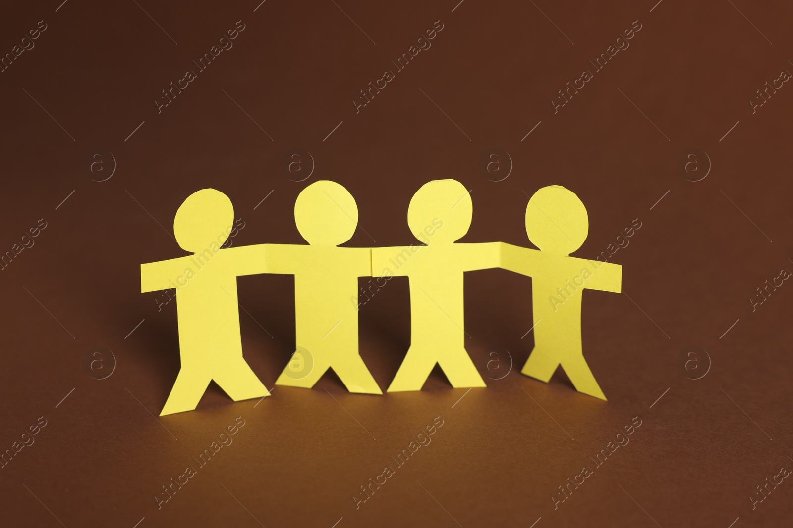 Paper figures of people holding hands on brown background, closeup Photo of Paper figures of people holding hands on brown background, closeup