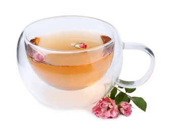 Photo of Aromatic tea in glass cup, roses and green leaves isolated on white