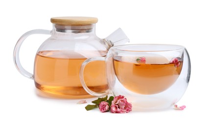 Photo of Aromatic tea in glass cup, teapot, roses and green leaves isolated on white