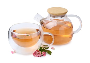 Photo of Aromatic tea in glass cup, teapot, roses and green leaves isolated on white