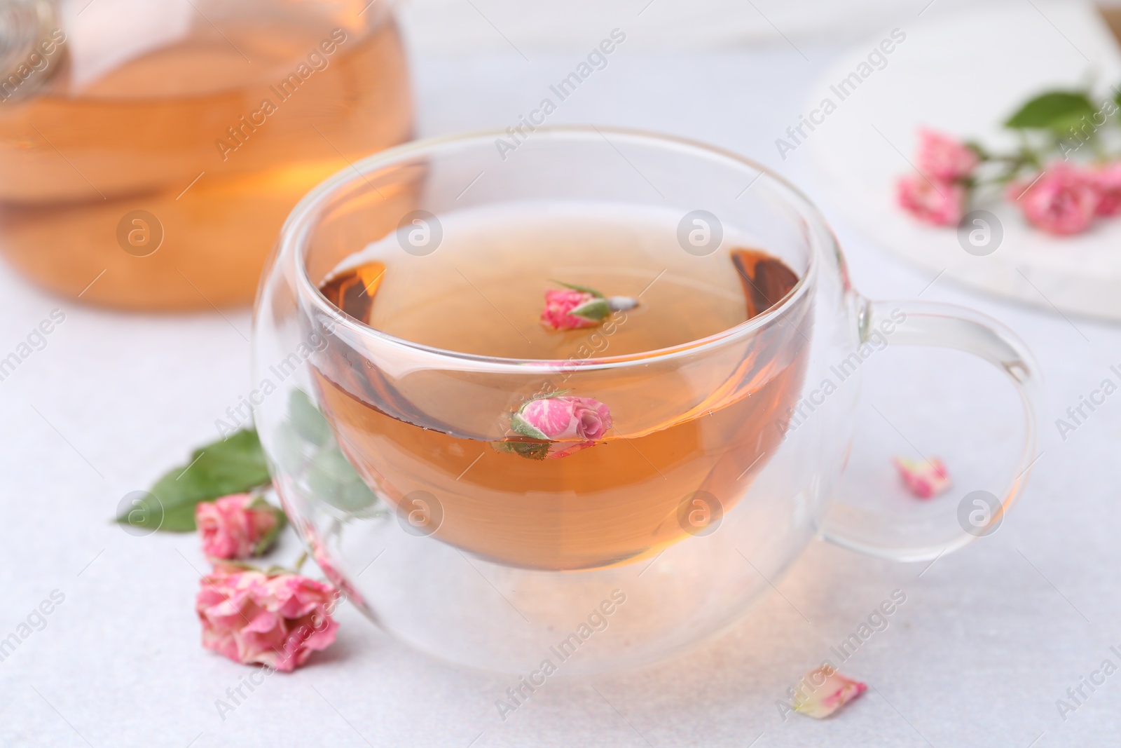 Aromatic tea in glass cup and roses on light table, closeup Photo of Aromatic tea in glass cup and roses on light table, closeup