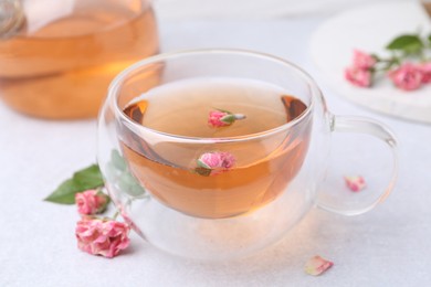 Photo of Aromatic tea in glass cup and roses on light table, closeup