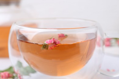Photo of Aromatic tea in glass cup and roses on table, closeup