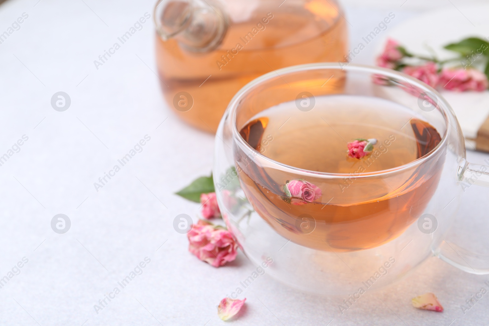 Aromatic tea in glass cup, teapot and roses on light table, closeup. Space for text Photo of Aromatic tea in glass cup, teapot and roses on light table, closeup. Space for text