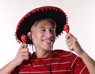 Photo of Happy man in black Flamenco hat playing maracas on white background