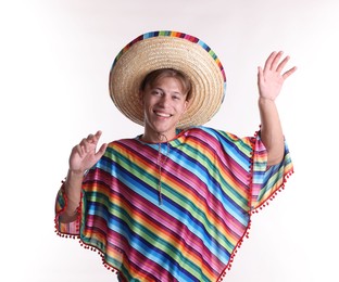 Photo of Smiling man in sombrero hat and colorful poncho dancing on white background