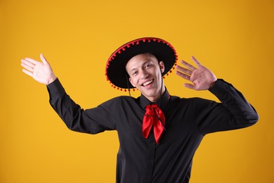 Photo of Portrait of smiling man in black Flamenco hat dancing on yellow background