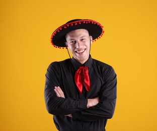 Photo of Portrait of smiling man in black Flamenco hat with crossed arms on yellow background