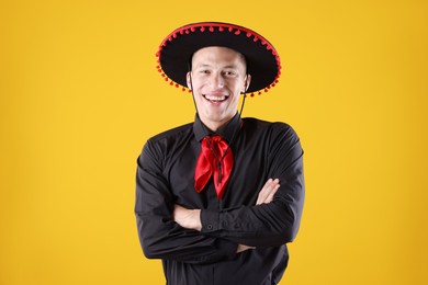 Photo of Portrait of smiling man in black Flamenco hat with crossed arms on yellow background