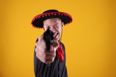 Photo of Happy man in black Flamenco hat with gun on yellow background